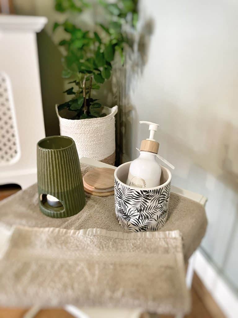 1. Groene en witte badkameraccessoires met botanisch patroon en groene kaars.