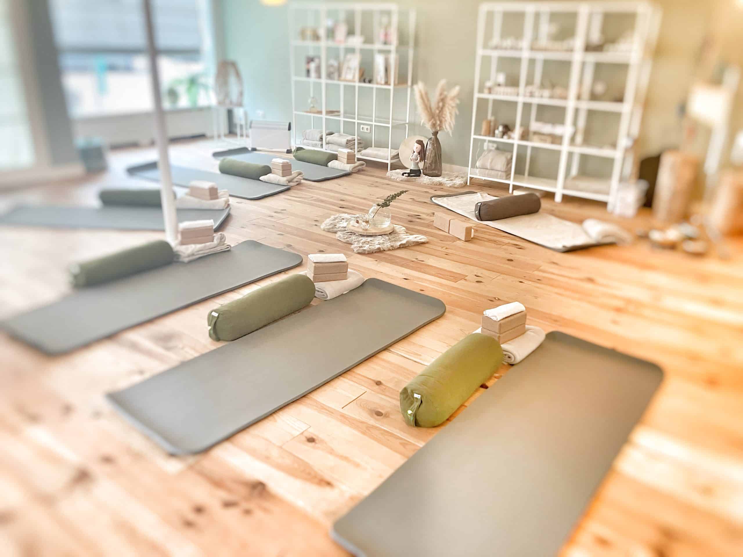 1. Yoga mats met bolster, handdoeken en blokken in een rustige, sfeervolle wellnessruimte.