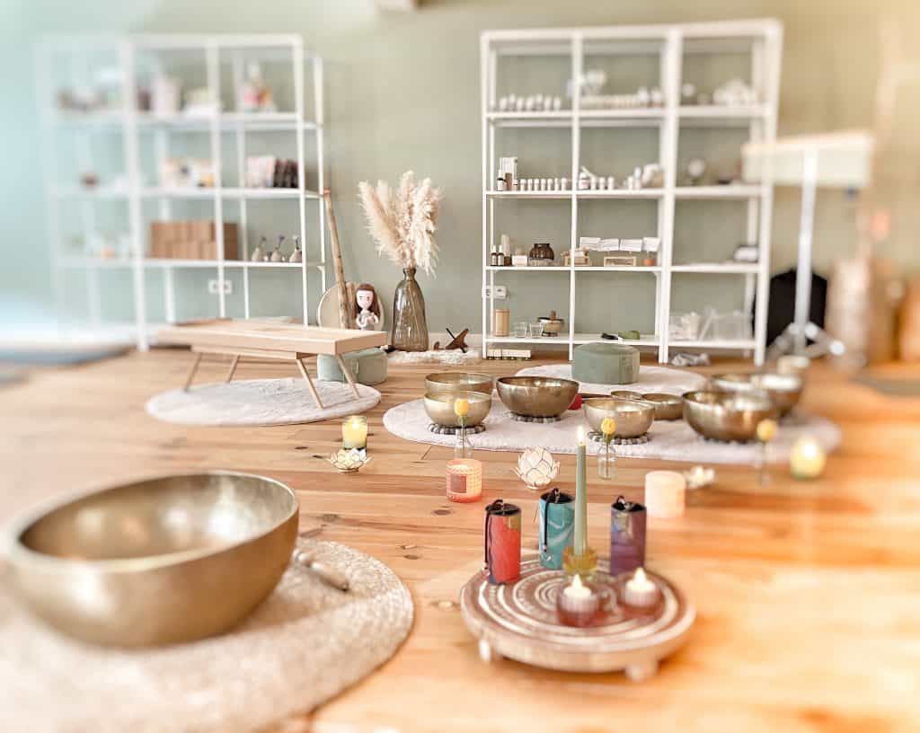 Zacht gekleurde meditatieruimte met kristallen klankschalen en kaarsen voor ontspanning en energiebalans.