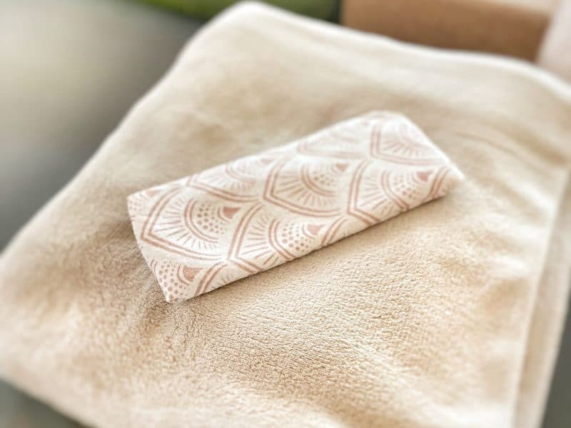 Zachte beige handdoek met geurige badhanddoek op bed, rust en ontspanning vullen de spa-omgeving.