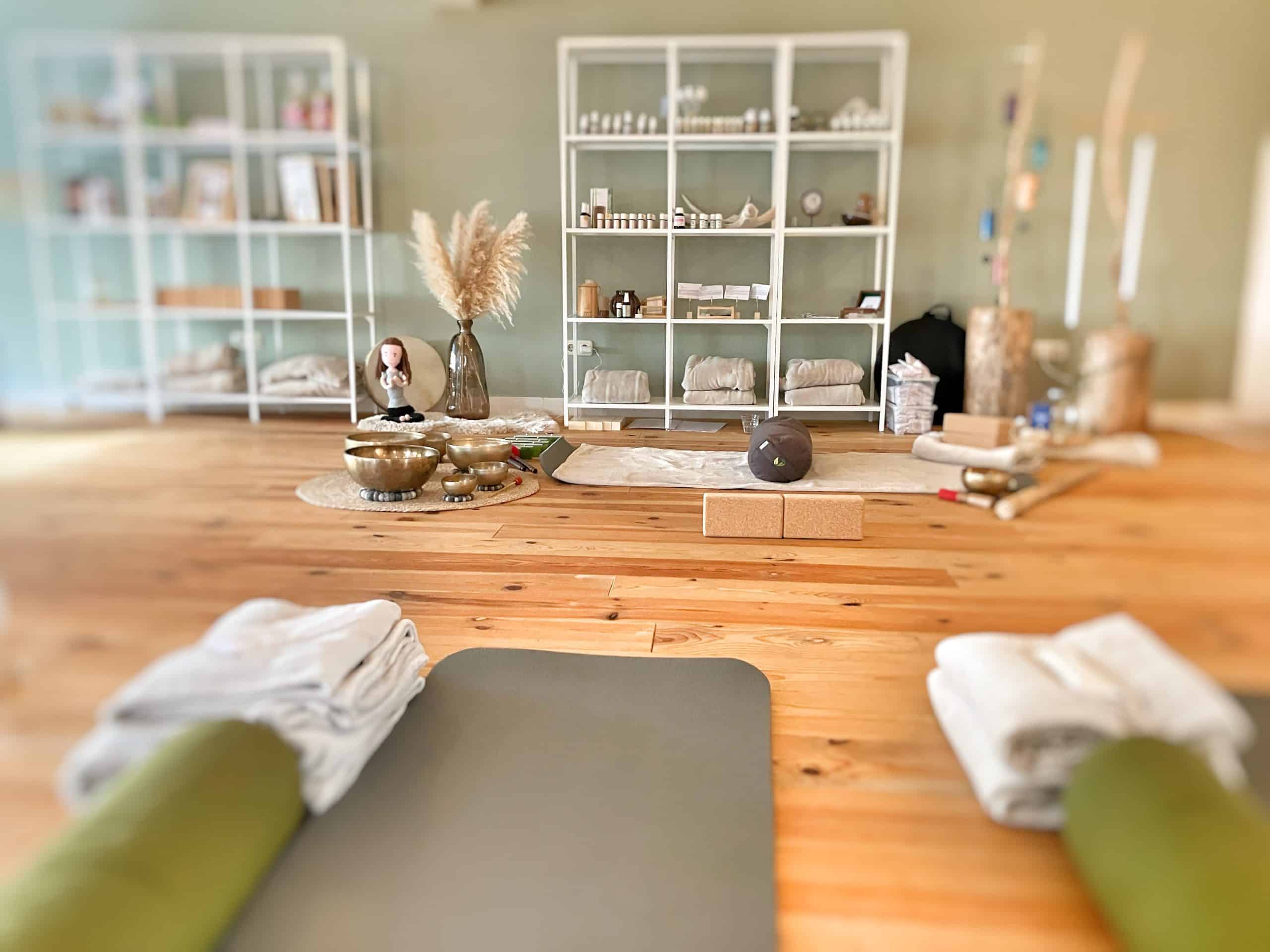 Rustgevende yoga- en meditatie ruimte met natuurlijke decoratie en houten vloer.